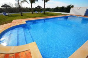 een groot blauw zwembad met twee stoelen in een tuin bij Villa Casa das Amendoeiras in Alcantarilha
