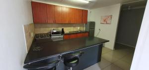 a kitchen with a black counter top and wooden cabinets at Beth El Guesthouse in Brackenfell