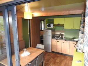 uma cozinha com uma mesa de madeira e paredes verdes em Camping Les Lavandes em Darbres