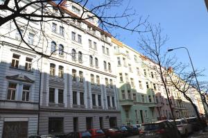 duży biały budynek z zaparkowanymi przed nim samochodami w obiekcie Family Apartments w Pradze