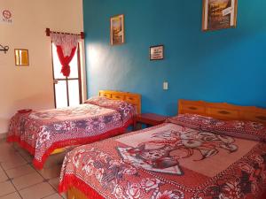 1 dormitorio con 2 camas, ventana y paredes azules en Hotel Lirice Colonial, en Comitán de Domínguez