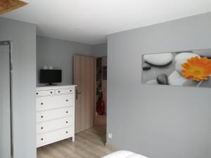 una camera da letto bianca con cassettiera e TV di Le petit poucet a La Bourboule Altre 5 foto