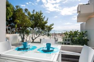 a white dining table and chairs with a view of the beach at Ciudad Blanca Apartment in Port d'Alcudia