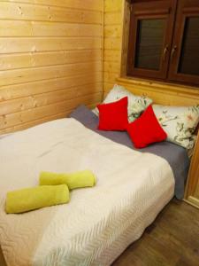 uma cama com almofadas vermelhas e amarelas em Całoroczne Domki "Stokrotka" em Solina