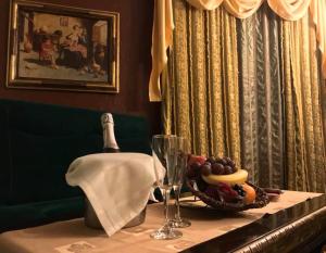 a table with a bottle of champagne and a bowl of fruit at Ambassador Hotel in Timişoara