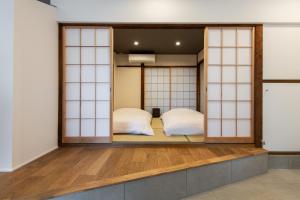 dwa łóżka w pokoju ze szklanymi drzwiami w obiekcie Kamin Kanazawa w mieście Kanazawa