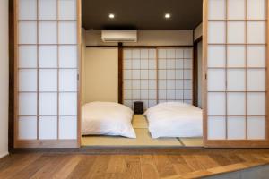 two beds in a room with glass doors at Kamin Kanazawa in Kanazawa