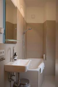 ein Badezimmer mit einem Waschbecken, einer Dusche und einer Badewanne in der Unterkunft LüneMitte - An der Münze in Lüneburg