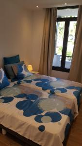 a bed with a blue and white comforter with a window at Pinien Platz in Cala Ratjada