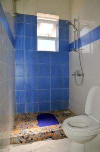 a blue tiled bathroom with a toilet and a window at Victoria Lake View Guesthouse & Safaris in Entebbe
