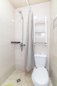 a white bathroom with a toilet and a shower at Guest house poligloti in Tʼelavi