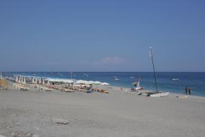 een strand met stoelen en parasols en de oceaan bij Appartamento Topazio in Letojanni