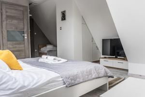 ein weißes Schlafzimmer mit einem Bett und einem TV in der Unterkunft MIŁOSZÓWKA in Witów