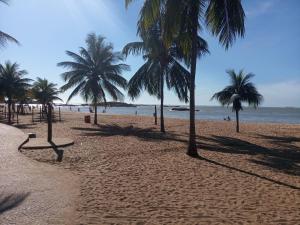 uma praia arenosa com palmeiras e o oceano em Apto Praia de Itapoã 2 qto c/ar em Vila Velha