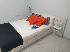 1 dormitorio con cama blanca y almohadas coloridas en APARTAMENTO CON ENCANTO Y UBICACIÓN PERFECTA en Cádiz