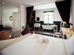 una camera con letto bianco e vasca da bagno di Nidhra Lanna Hotel a Chiang Mai