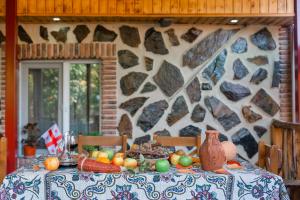 a table with fruits and vegetables on it with a stone wall at Guest house poligloti in Telavi