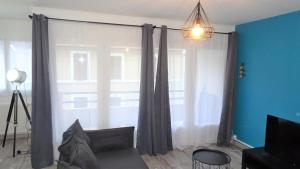 a living room with a couch and a large window at Grand appartement T3/T4 proche des berges du Cher in Montluçon
