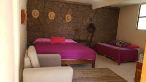 Hotel Juliantla في Juliantla: غرفة نوم بها سريرين وكرسي بداخلها