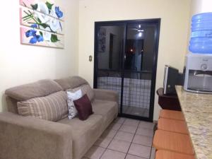 a living room with a couch in a kitchen at Apartamento "Pé na Areia" Mongaguá in Mongaguá