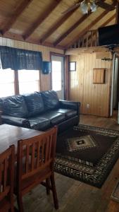 a living room with a black leather couch and a table at Chama River Bend Lodge in Chama