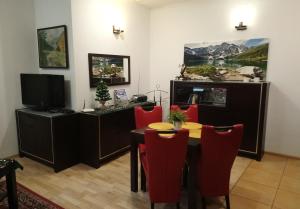 a dining room with a table and red chairs at Apartament Radowid 15 w centrum z basenem in Zakopane