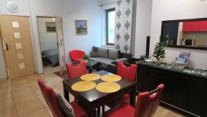 a living room with a table and red chairs at Apartament Radowid 15 w centrum z basenem in Zakopane