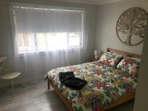 1 dormitorio con 1 cama con colcha de flores y ventana en Lautan Cronulla Beach en Cronulla
