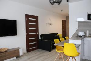 ein Wohnzimmer mit einem Tisch und gelben Stühlen in der Unterkunft Apartmán Olaf Tatranská Lomnica in Tatranská Lomnica