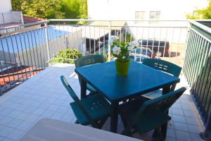 une table bleue avec des chaises et un vase de fleurs sur le balcon dans l'établissement Delizioso Bilocale in Centro, à Conselice
