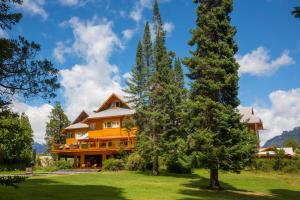 a large wooden house with trees in front of it at Hostería Isla Victoria Lodge in Isla Victoria