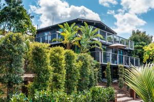 an exterior view of a house with bushes at Moana on Waikare - You've Got It Maid in Oneroa