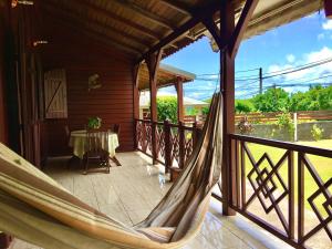 a porch with a hammock and a table on it at Chambre à louer chez l'habitant dans Villa Créole Authentique et en Bois in Trois-Rivières