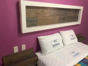 a bedroom with purple walls and a bed with two pillows at Hotel Occidental in Guadalajara