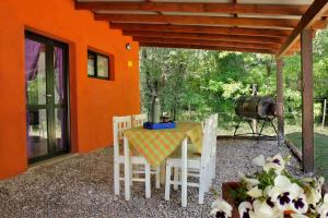 una casa naranja con mesa, sillas y parrilla en Cabañas Inti Wara en Los Reartes