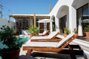 une terrasse avec des chaises longues et une piscine dans l'établissement Casa Beu, à Puerto Escondido