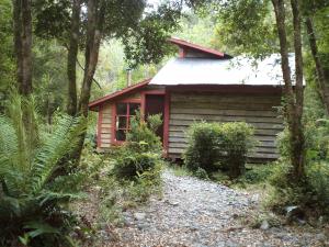 una cabaña roja en el bosque con un camino de grava delante en Alojamiento junto al mar, en Chaitén