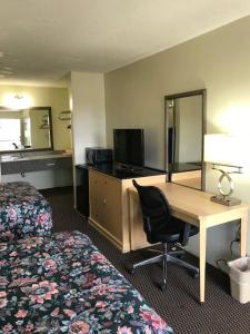 Una habitación de hotel con un escritorio y una cama. en WESTERN MOTEL, en Brinson Crossing