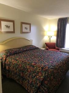 una habitación de hotel con una cama y una silla en WESTERN MOTEL, en Brinson Crossing