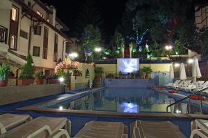 a swimming pool at night with chairs and a television at Aquilon Hotel & Thermal Pools in Banya