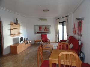 a living room with a red couch and a table at Playamarina 2 Reception Cabo Roig in Playas de Orihuela