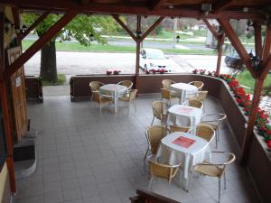 a patio with white tables and chairs and flowers at Czermann Panzió és Étterem in Oroszlány
