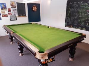 a green pool table in a room with a chalkboard at Clive Colonial Cottages in Clive