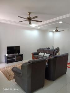 ein Wohnzimmer mit Sofas und einem Flachbildfernseher in der Unterkunft Rara Homestay Kuala Kangsar in Kuala Kangsar