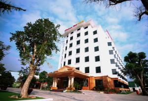 un hotel con un edificio blanco con un árbol en Thông Đỏ Hotel, en Vinh