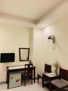 een woonkamer met een tv en een tafel en stoelen bij Ha Anh Hotel - Mui Ne in Mũi Né