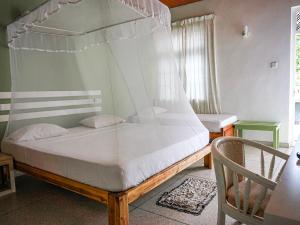 a bedroom with a canopy bed and a chair at Nuga Eden Tangalle in Tangalle