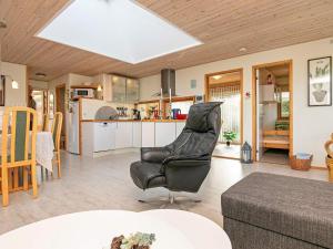 a living room with a chair and a kitchen at Simplistic Holiday Home in Lolland with Terrace in Rødby
