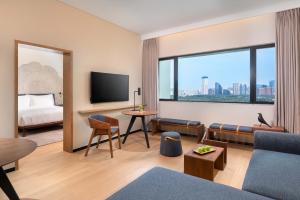 a hotel room with a couch and a tv and a bed at BEI Zhaolong Hotel, a JdV by Hyatt in Beijing