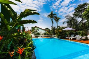 a swimming pool in front of a house with palm trees at Miana Resort Phu Quoc in Phu Quoc